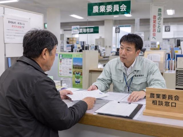 役場の農業委員会窓口で手続きの相談をする男性