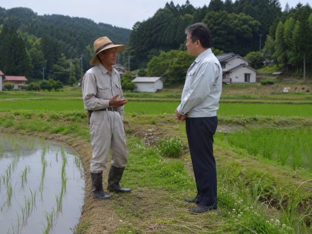 近隣農家とあぜ道で譲渡の相談をする様子