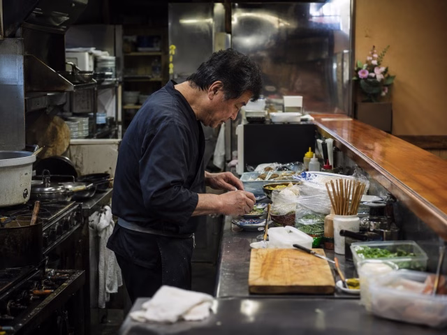 厨房で一人仕込みや片付けに追われ疲弊する地方飲食店の店主