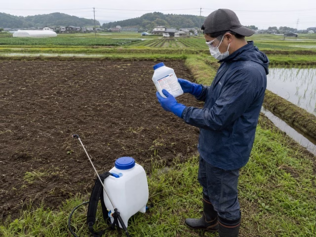 除草剤のラベルを確認してから散布準備をする農家